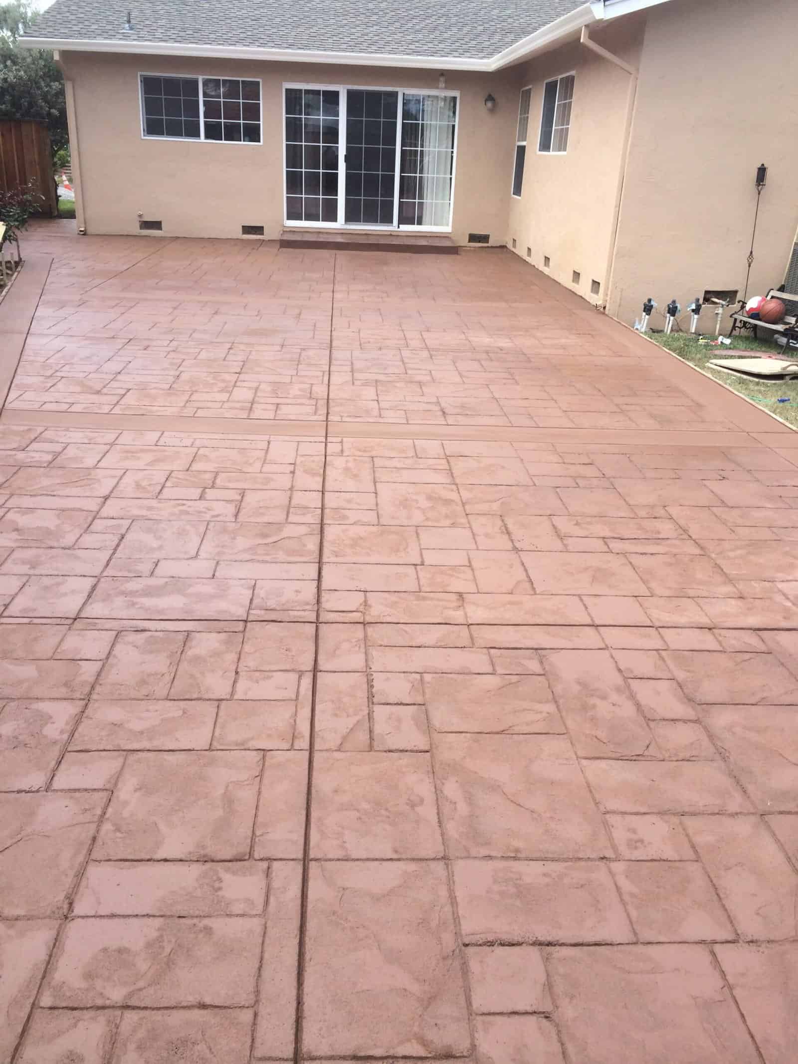 Newly poured stamped concrete backyard patio with decorative pattern.