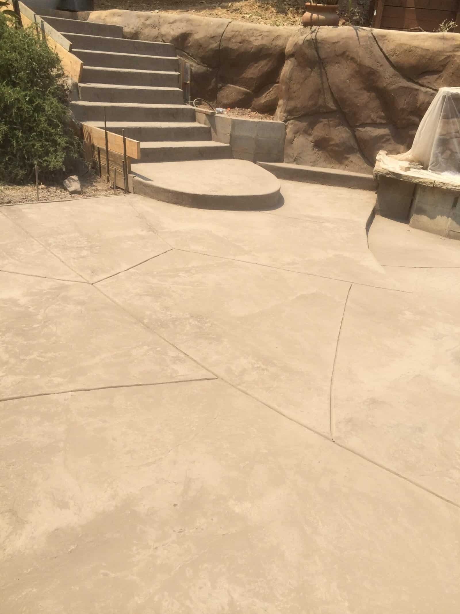 Concrete stairs and patio with custom stamped concrete design, curves, and steps for outdoor landscaping.