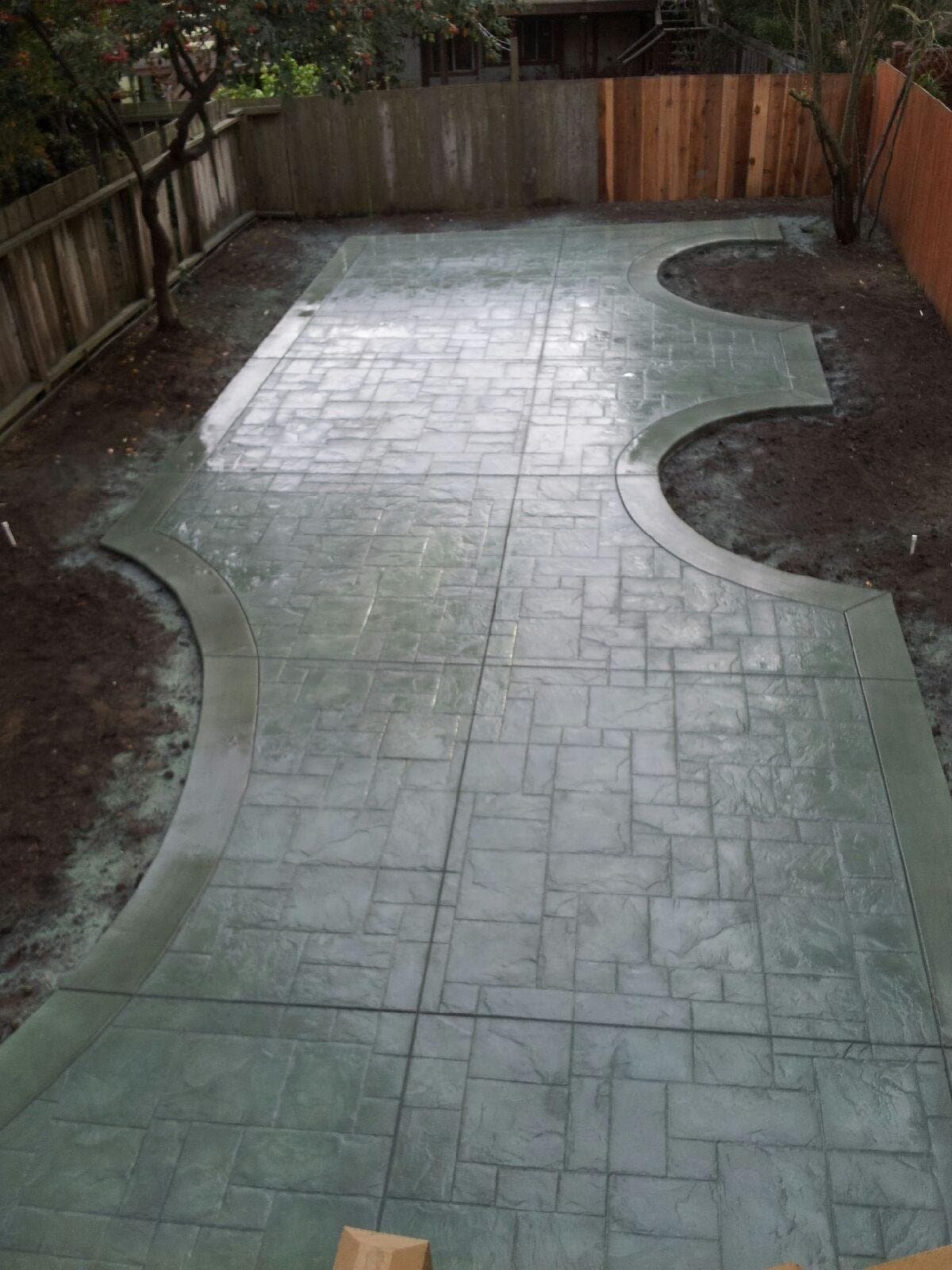 Stamped concrete patio with decorative edging and garden beds, completed by Ultimate Concrete Construction Inc.