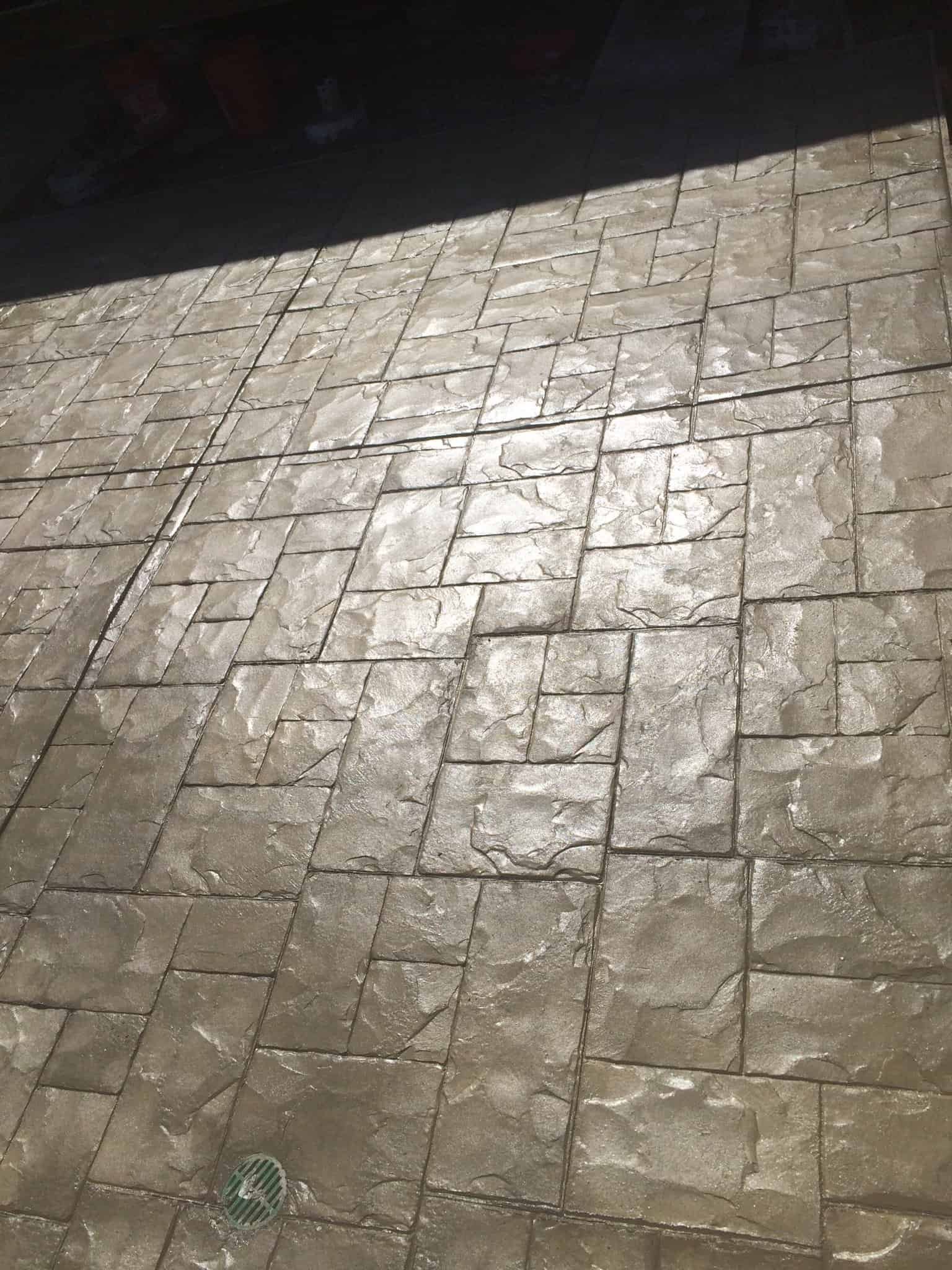 Concrete stamped patio with textured stone pattern in neutral tones for outdoor surface enhancement.