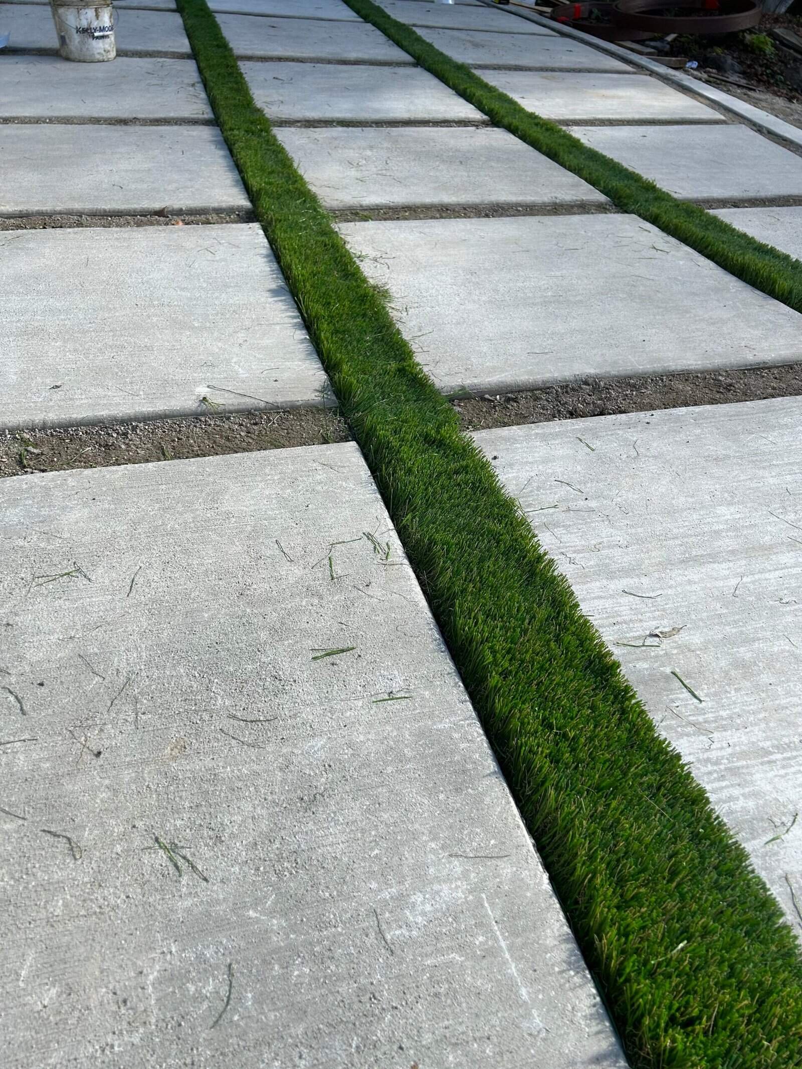 Concrete driveway with grass strips for aesthetic appeal and drainage improvement.